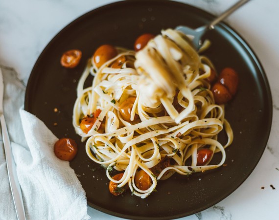 Pasta met tomaat op een donker bord — sfeerbeeld