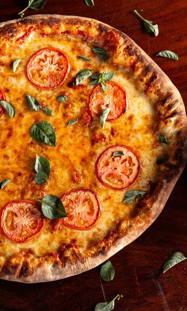 Pizza met tomaat en basilicum — sfeerbeeld